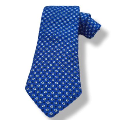 A blue necktie with a repeating small white and light blue geometric pattern, shown on a white background with a soft drop shadow.